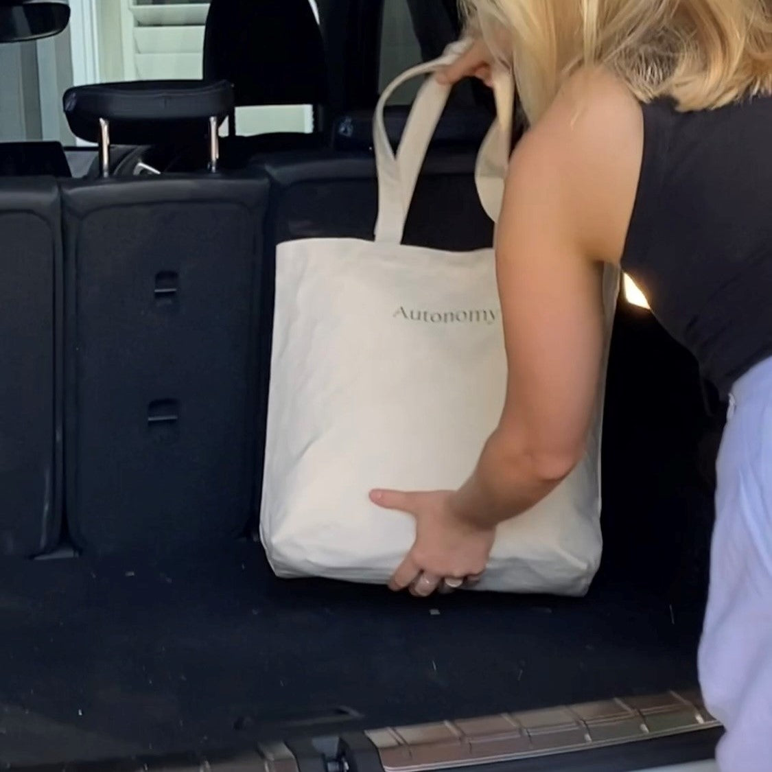 woman putting her autonomy tote bag in the boot of her car